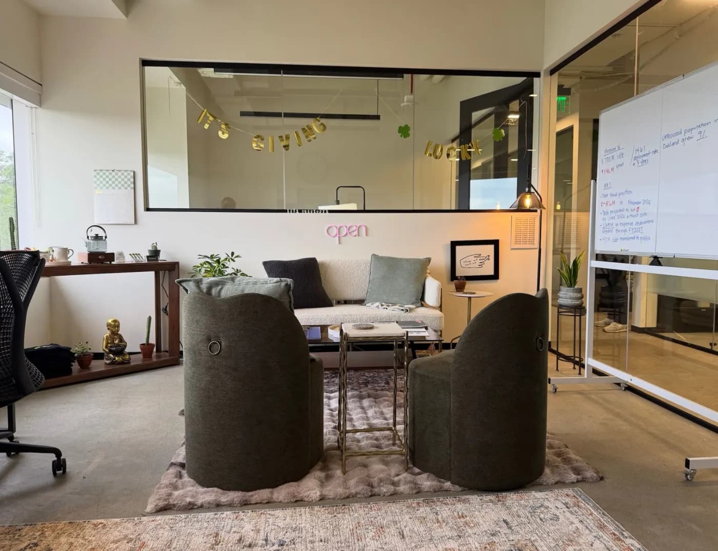 The Offboard office in Concord: two armchairs and a sofa around a small table, with a neon open sign on the wall